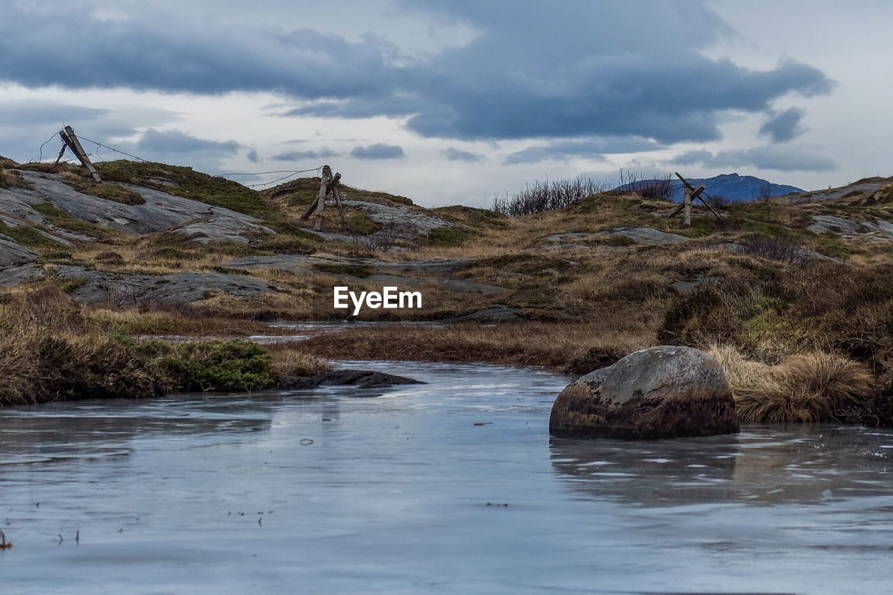 SCENIC VIEW OF RIVER AND MOUNTAINS AGAINST CLOUDY SKY