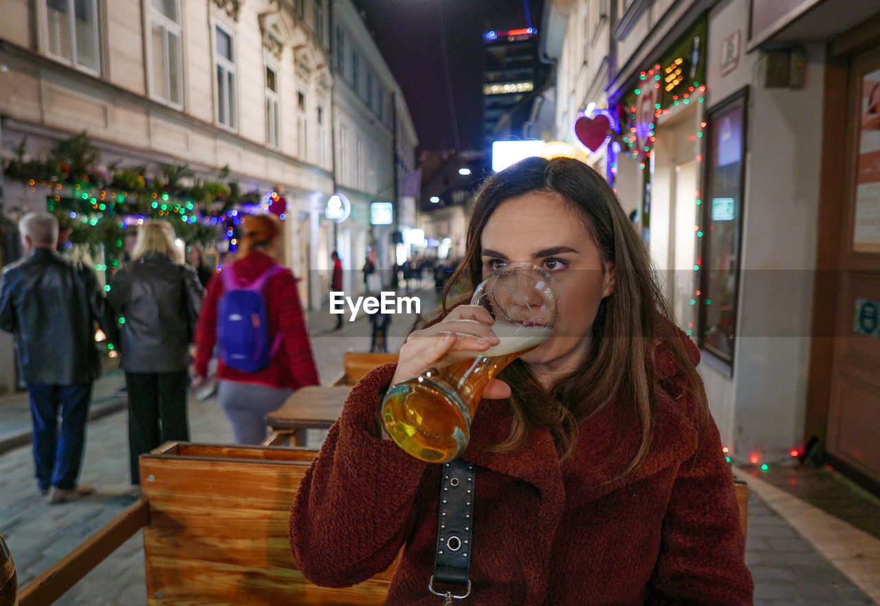 Woman drinking beer while sitting at outdoor cafe 