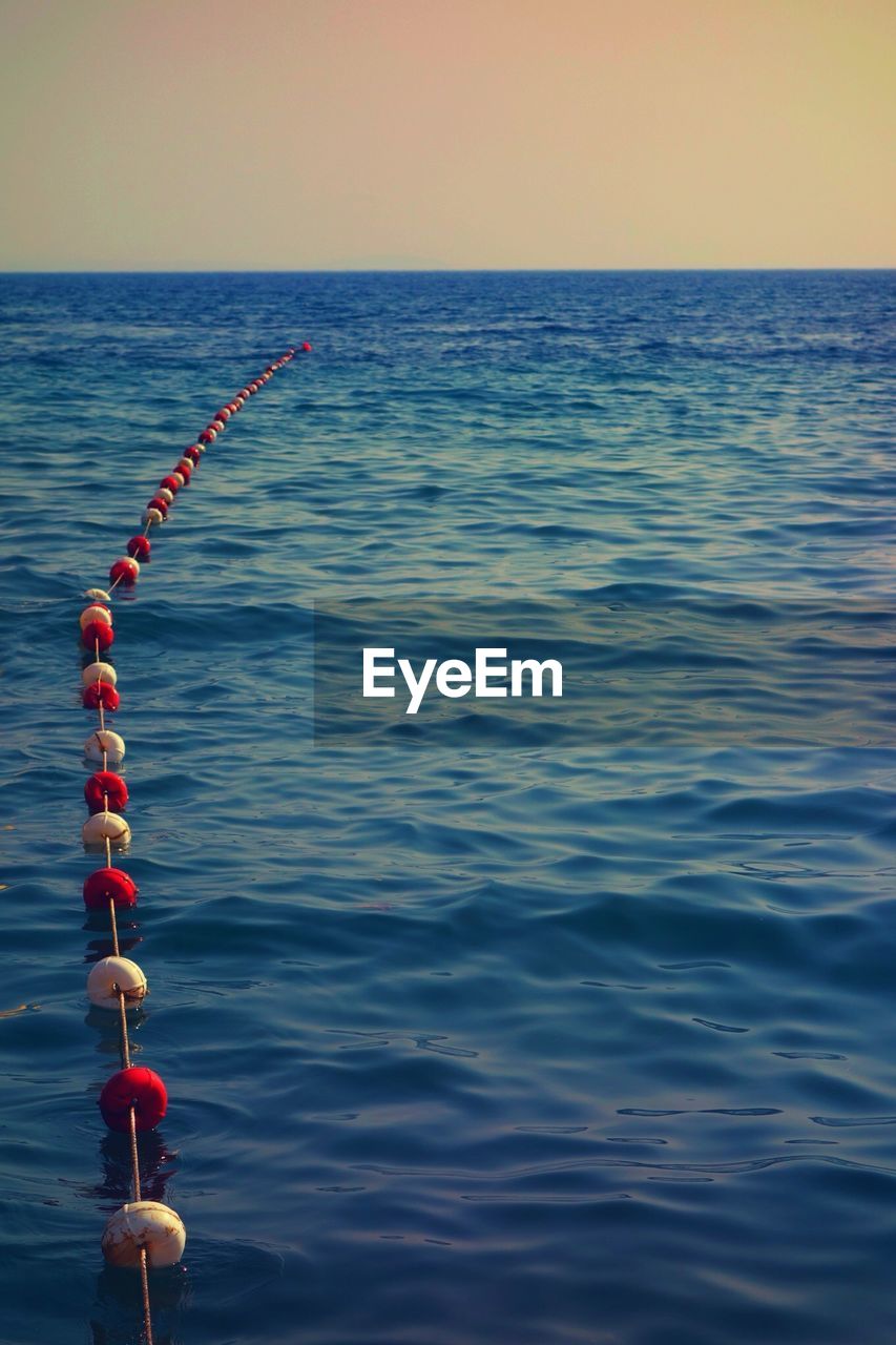 CLOSE-UP OF WATER HANGING ON SEA AGAINST SKY