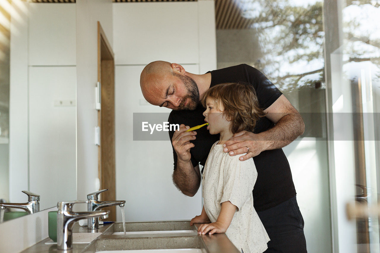 Father brushing son's teeth in bathroom