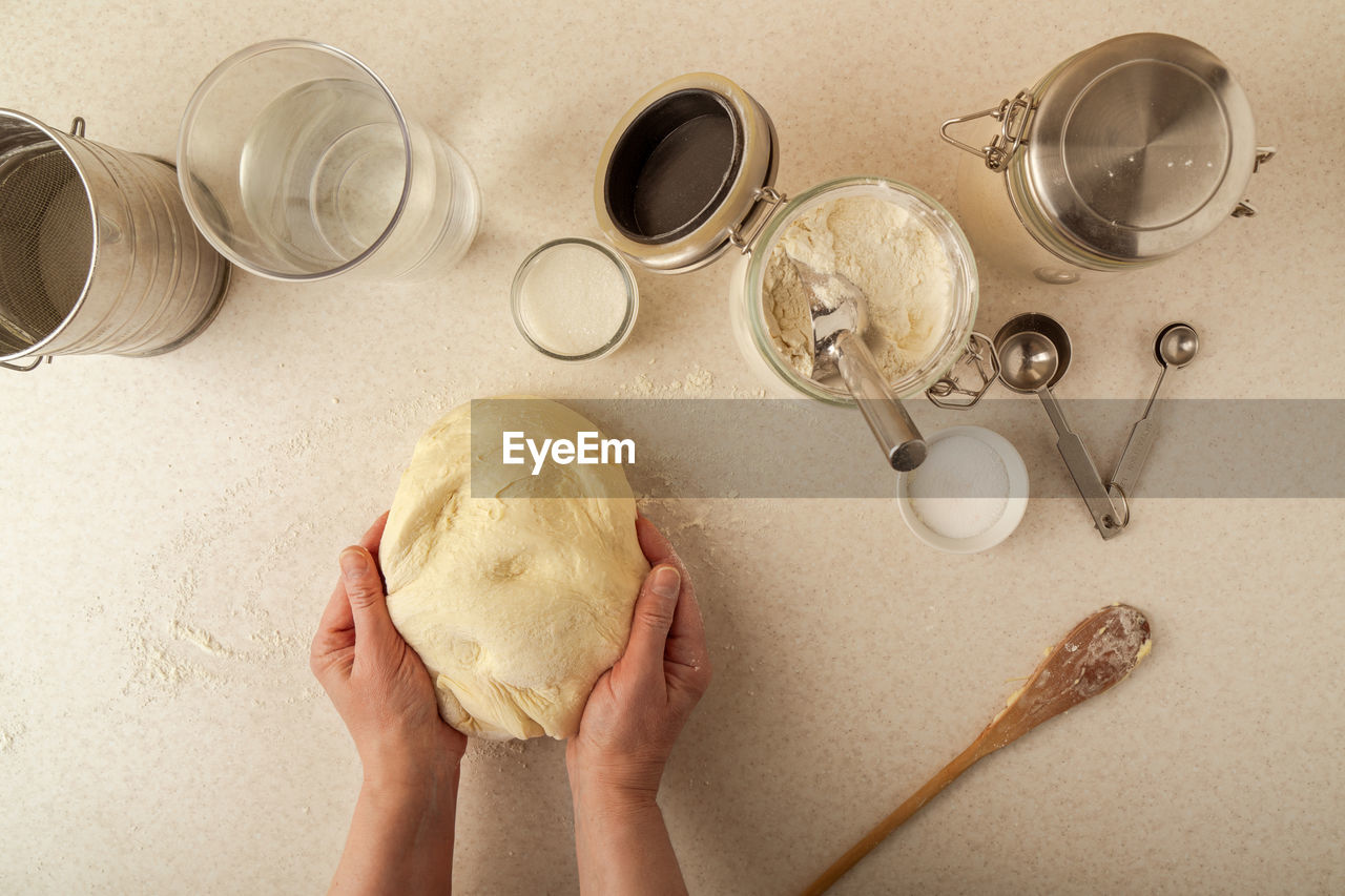 Woman's hands kneading dough on kitchen table, top view. horizontal image.