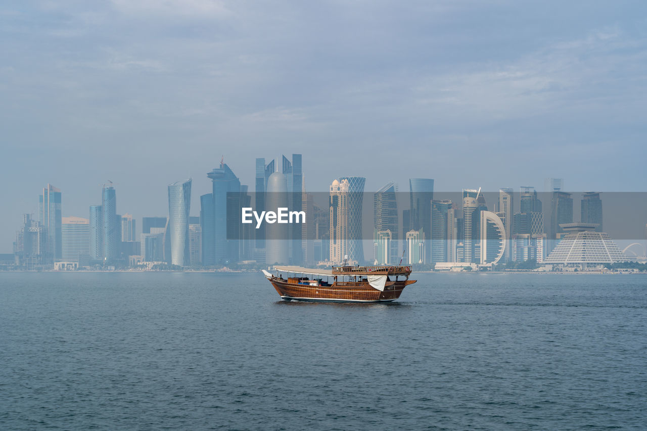 A traditional dhow in doha, qatar with the city's modern skyline in the background.