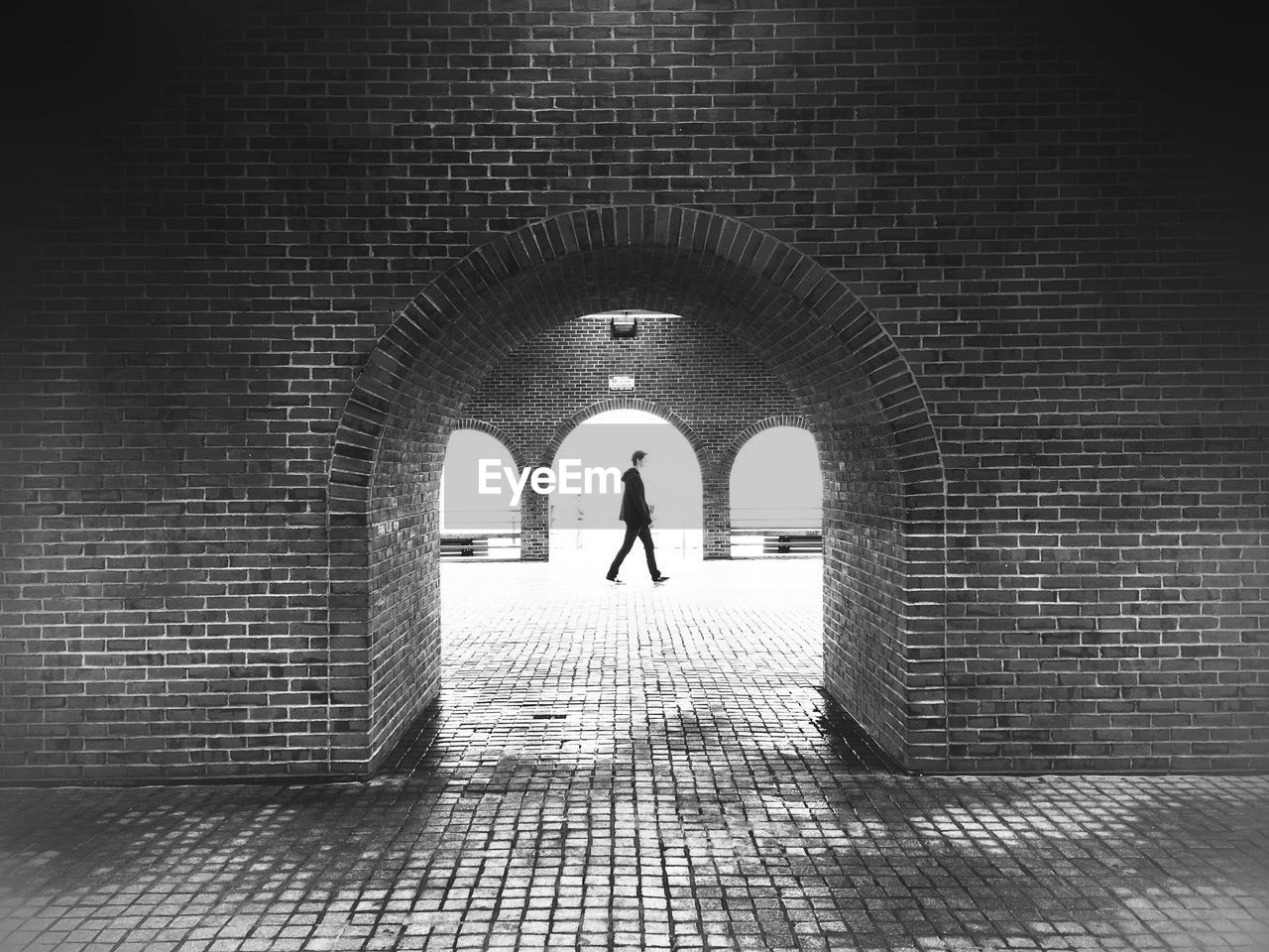 Man walking on footpath seen from archway