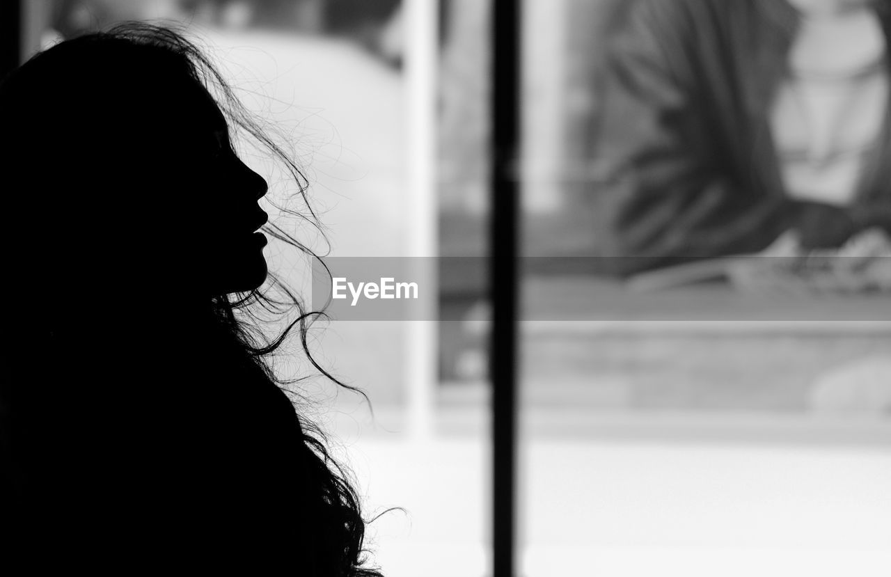 Rear view of woman looking through window