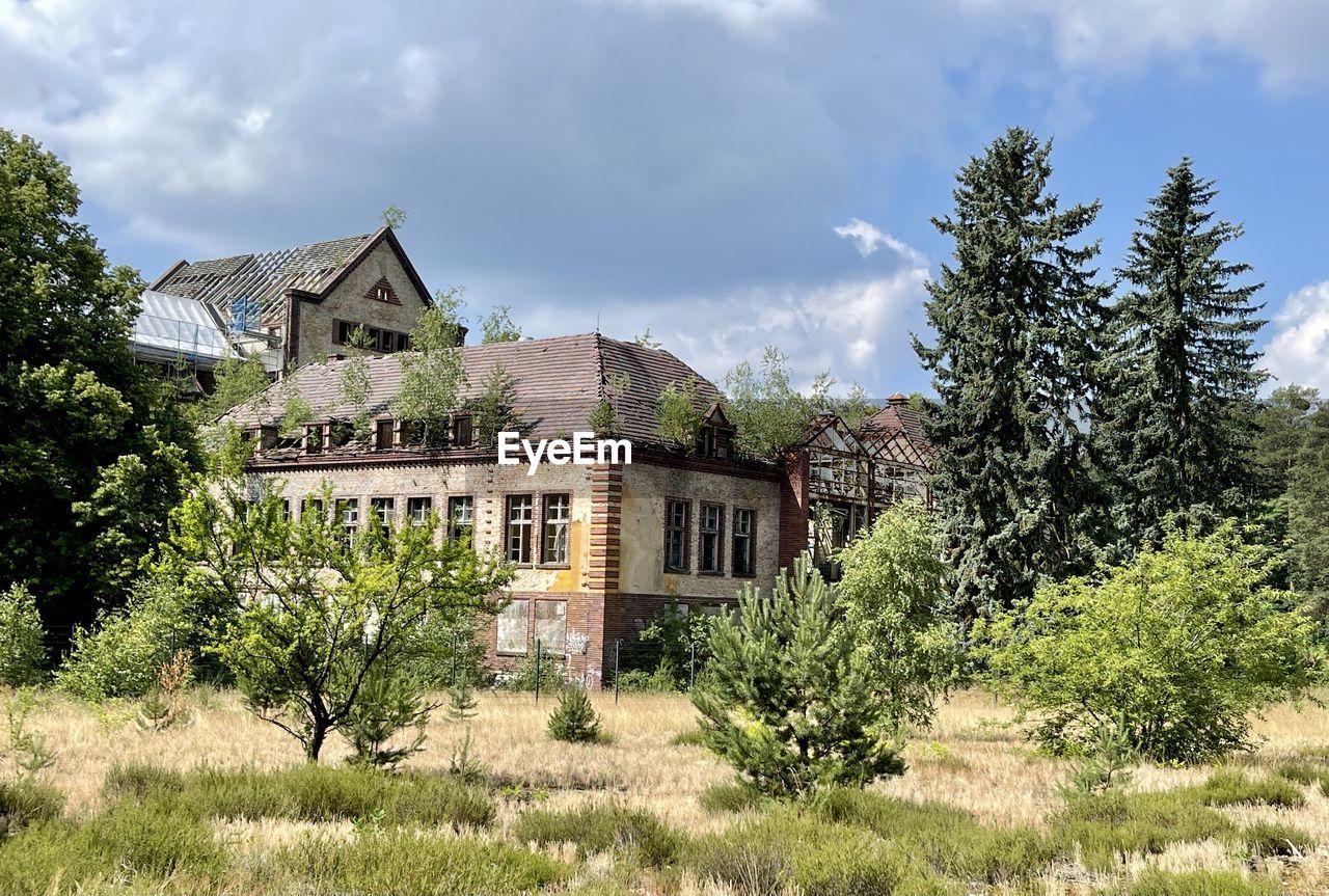 Old building by trees against sky