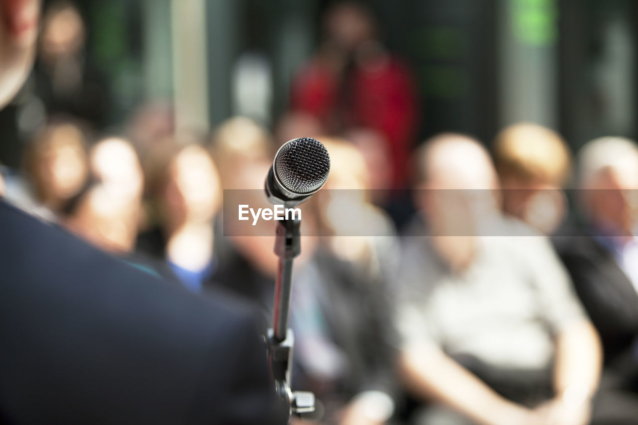 Midsection of microphone against crowd