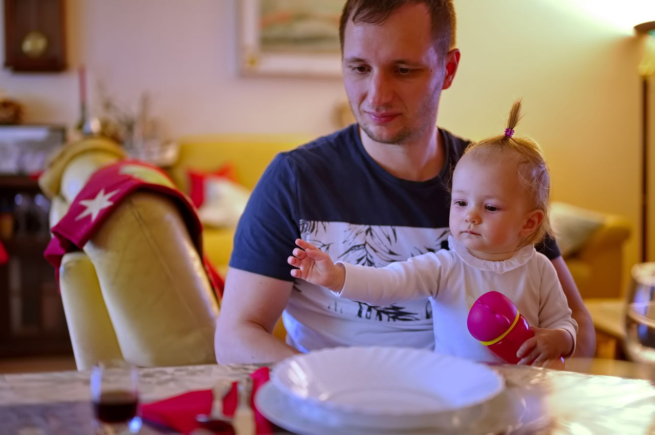 Father sitting at the table and holding his little baby girl