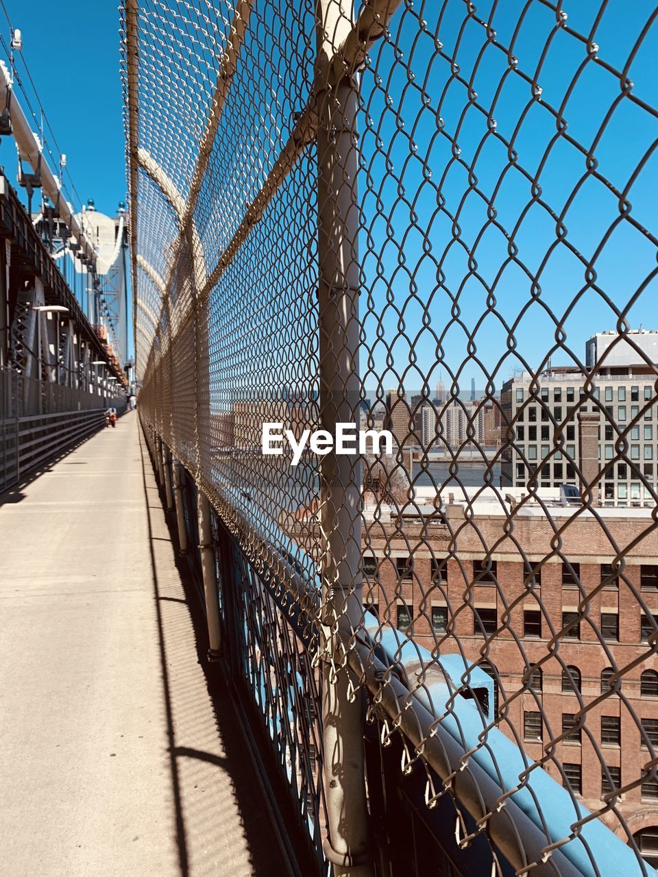 Chainlink fence against sky in city with bike lane over nyc bridge