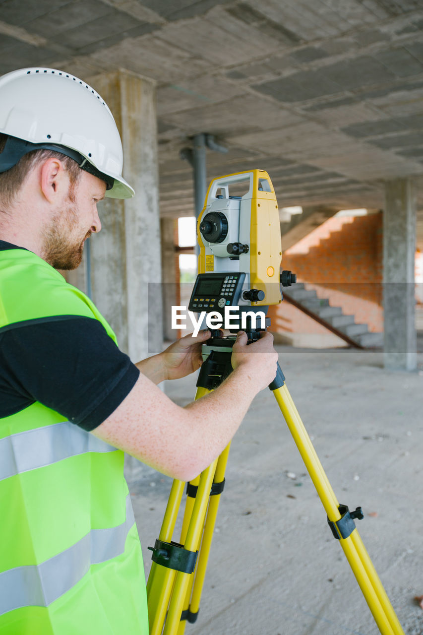Surveyor engineer working at construction site with measuring equipment (total station)