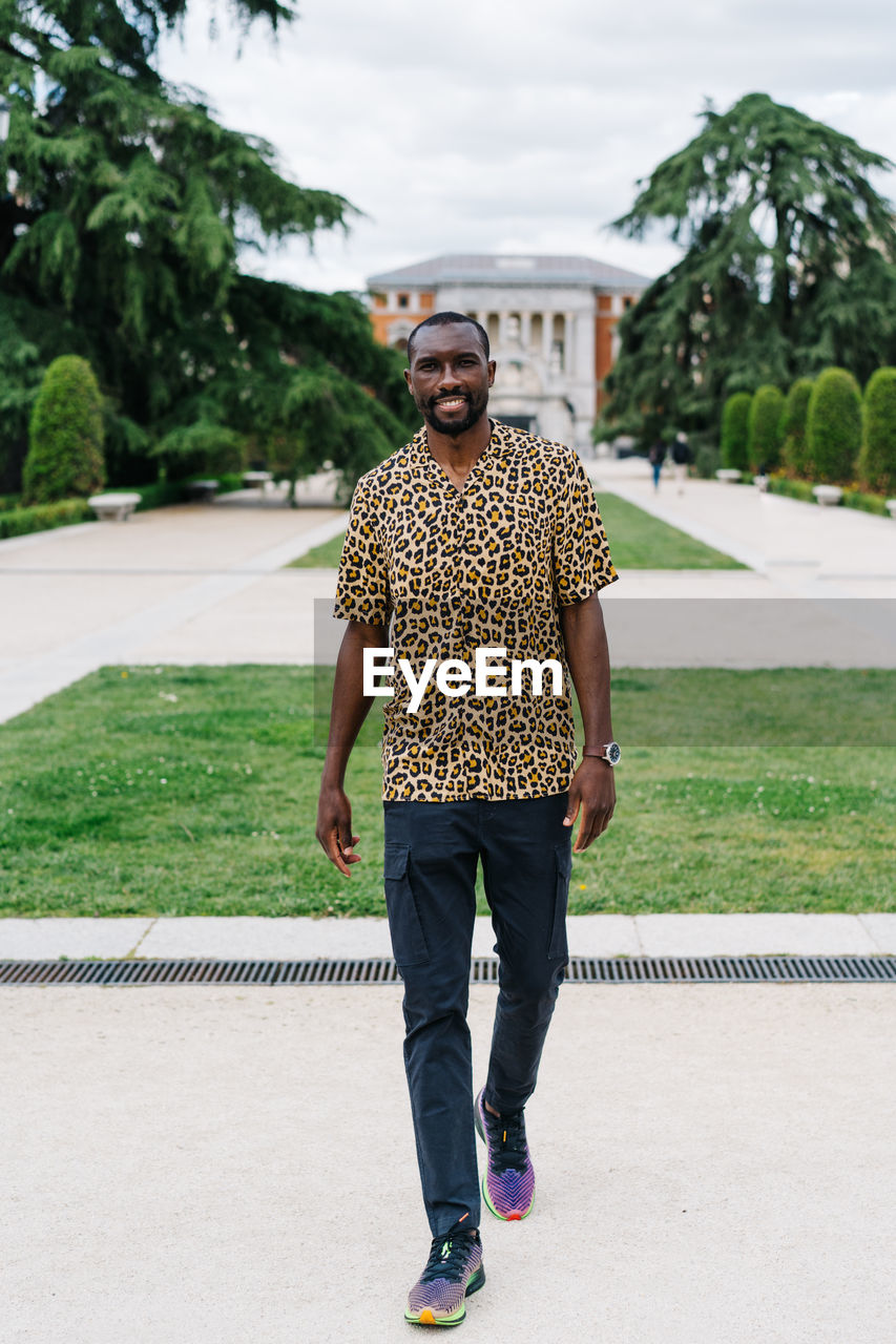 Positive afro american stylish man in european city with electronic device