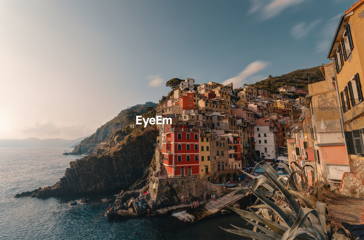 Buildings by sea against sky