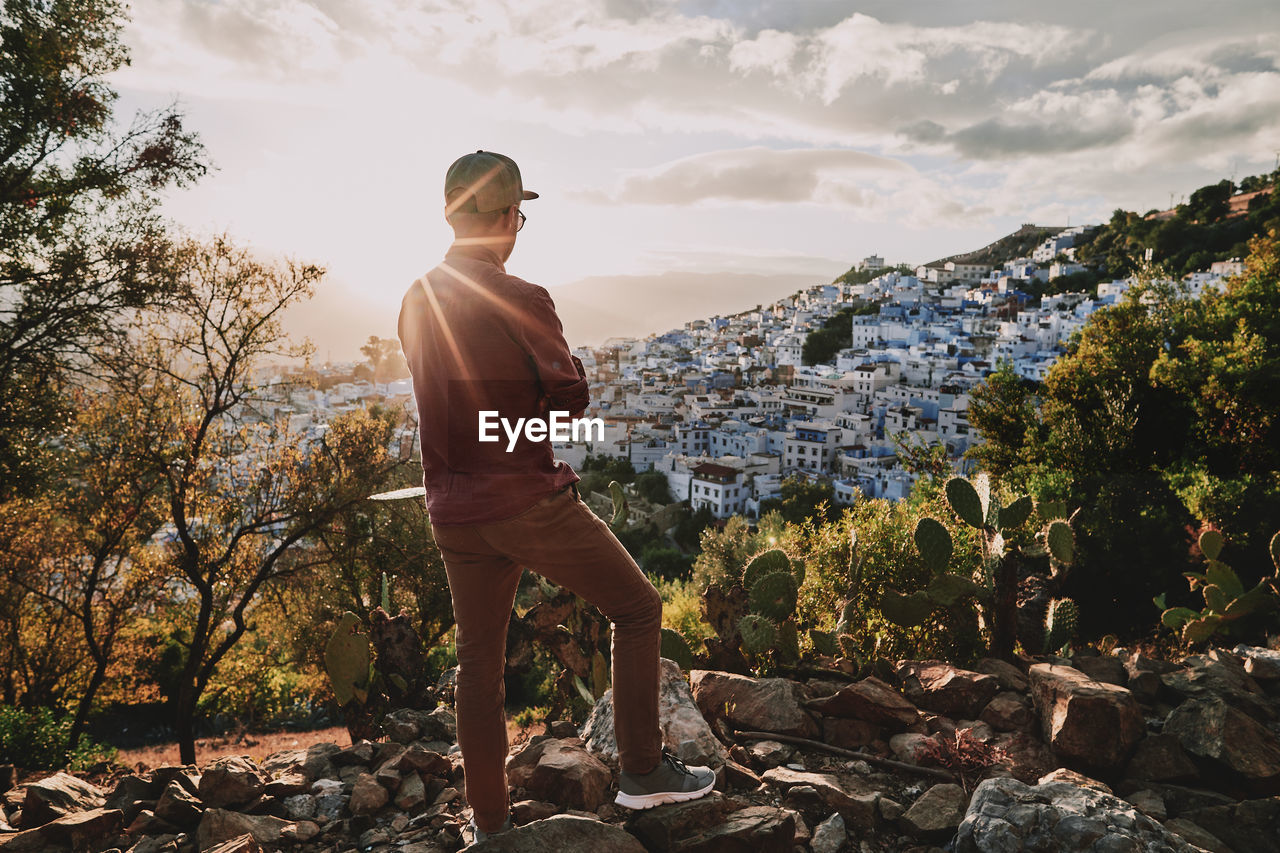 Young adult standing at a viewpoint, looking over chefchaouen, morocco at sunset