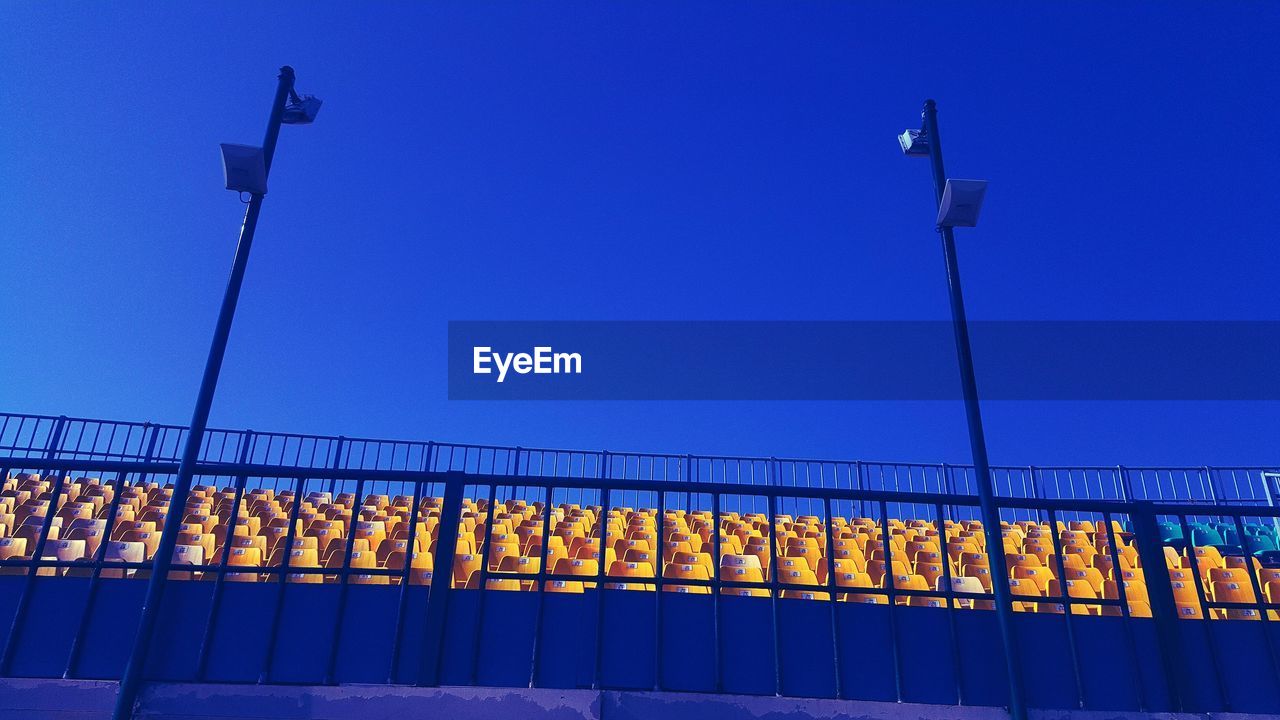 Low angle view of chairs in stadium against blue sky at night