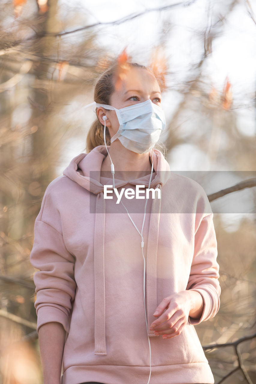 Woman wearing mask standing in forest