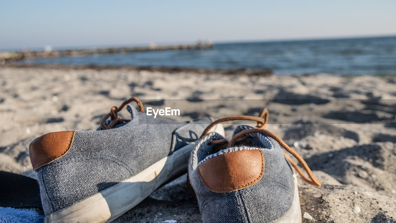 HIGH ANGLE VIEW OF SHOES ON BEACH AGAINST SKY