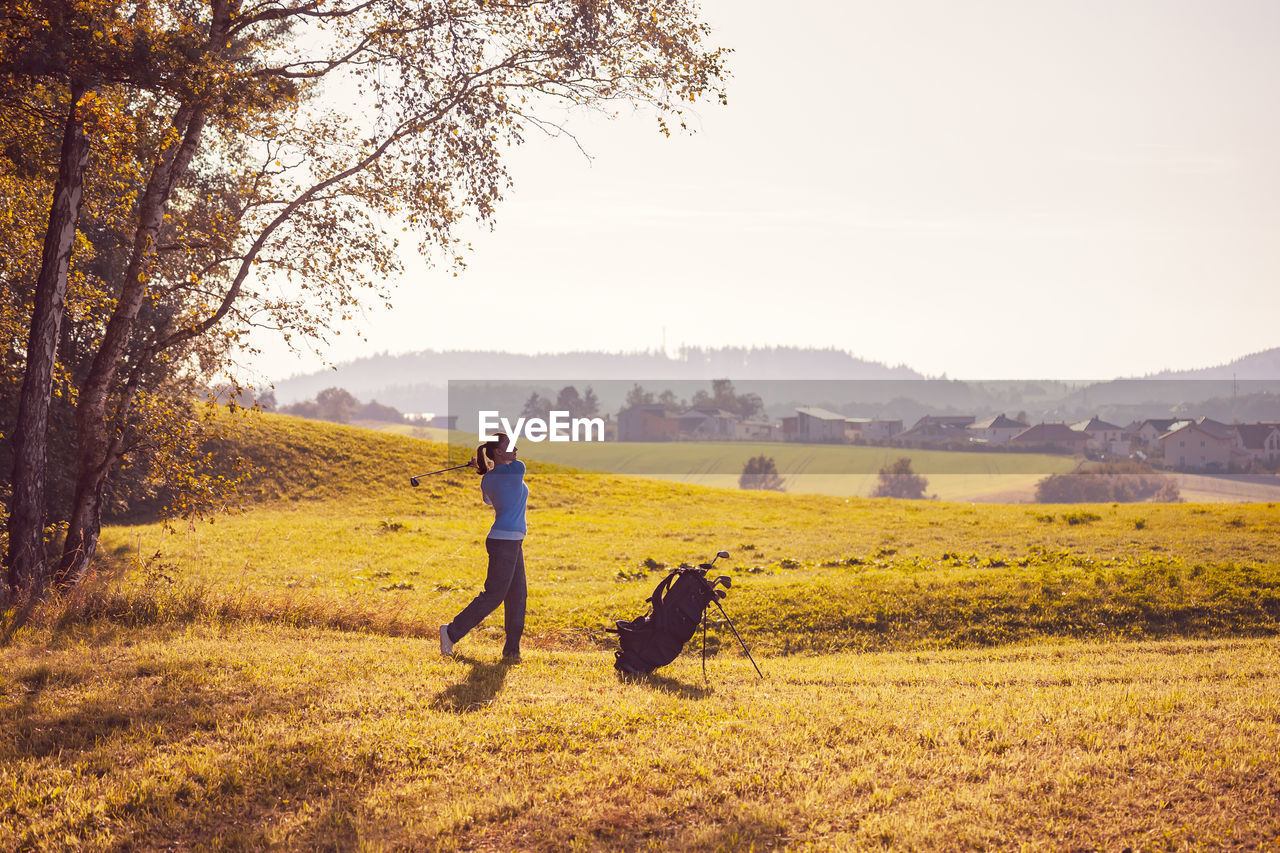 Side view of woman playing golf on grassy land