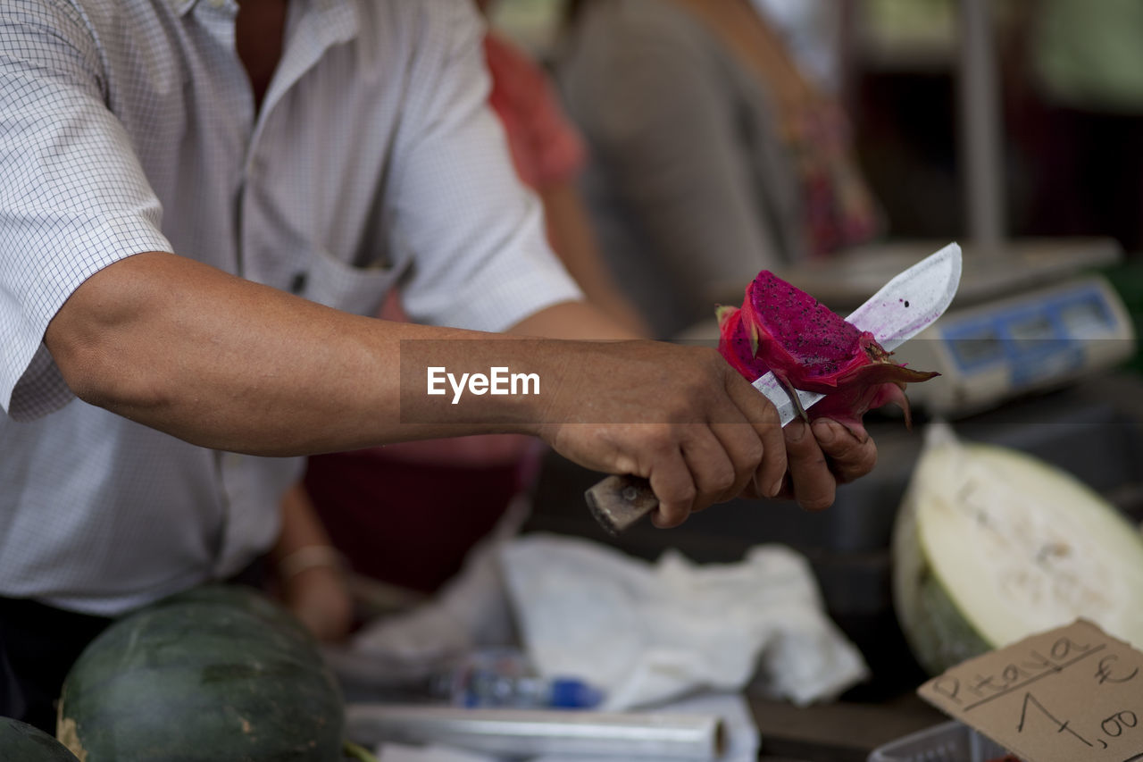 Midsection of market vendor cutting pitaya