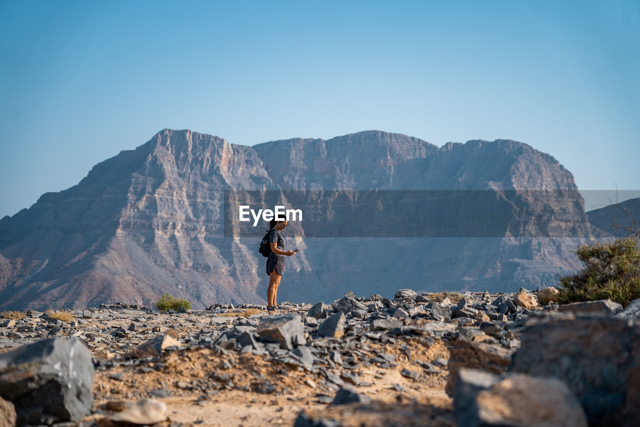 Full length of woman standing on rocks against mountains