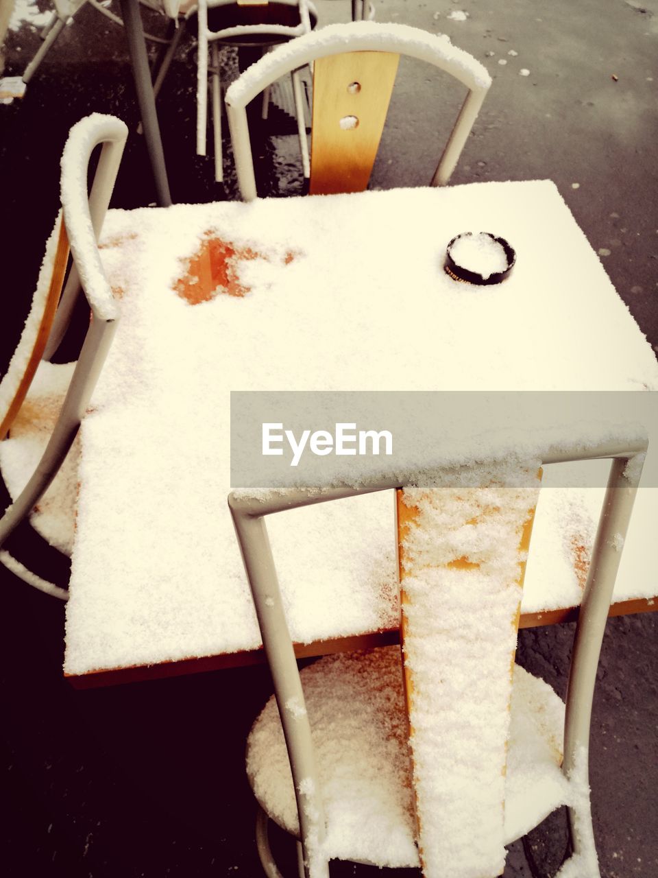 High angle view of frozen table and chairs at sidewalk cafe during winter