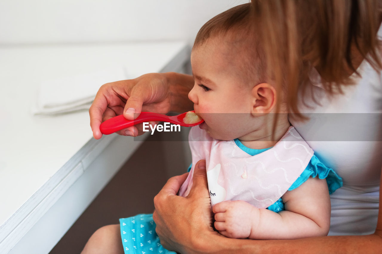 Mother feeding cute baby girl vegetable puree from a spoon. healthy eating nutrition for little kids