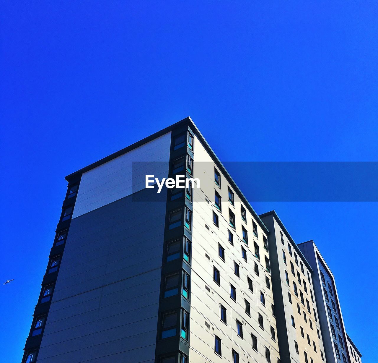 LOW ANGLE VIEW OF GLASS BUILDING AGAINST CLEAR BLUE SKY