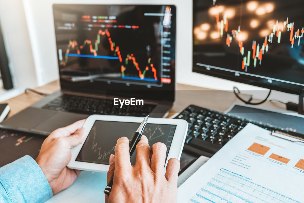 Cropped hands of businessman analyzing stock market data over digital tablet in office