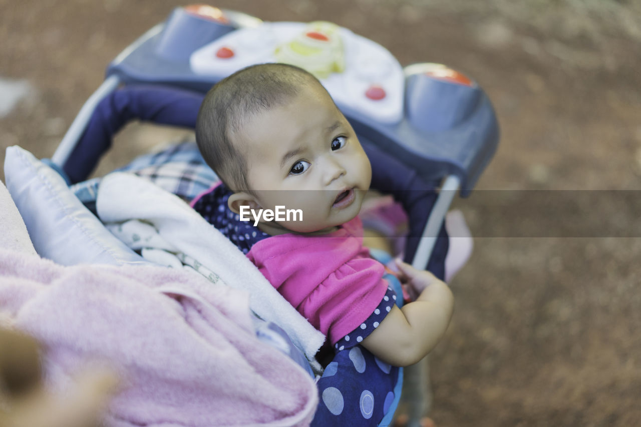 Portrait of baby girl sitting in stroller