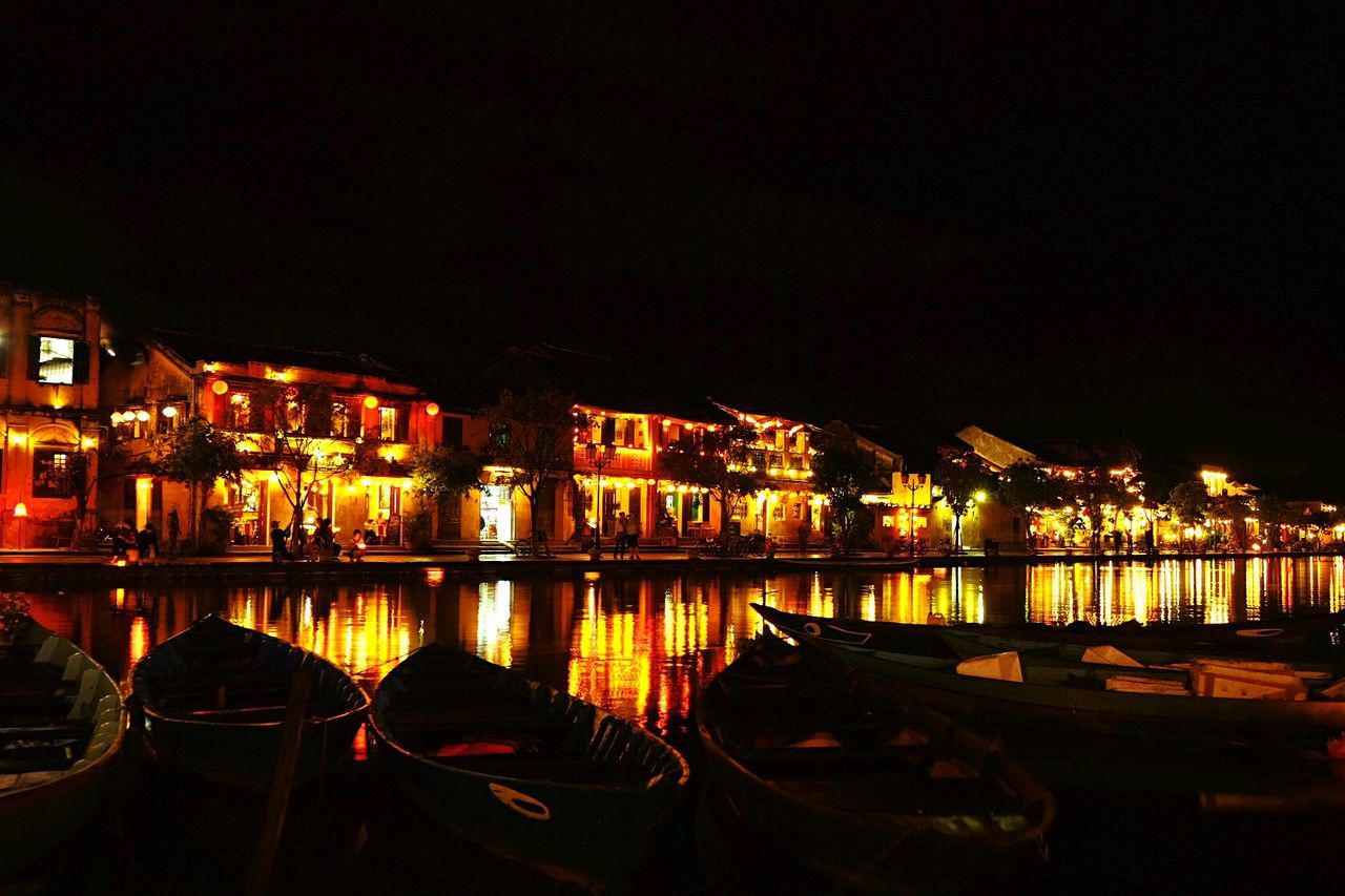 BOATS MOORED AT ILLUMINATED HARBOR AGAINST SKY AT NIGHT