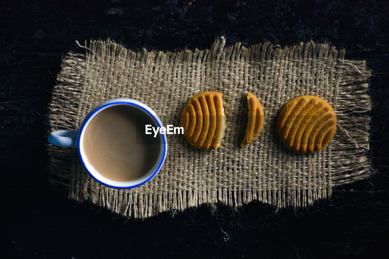 A cup of tea with biscuits on old wooden dark background