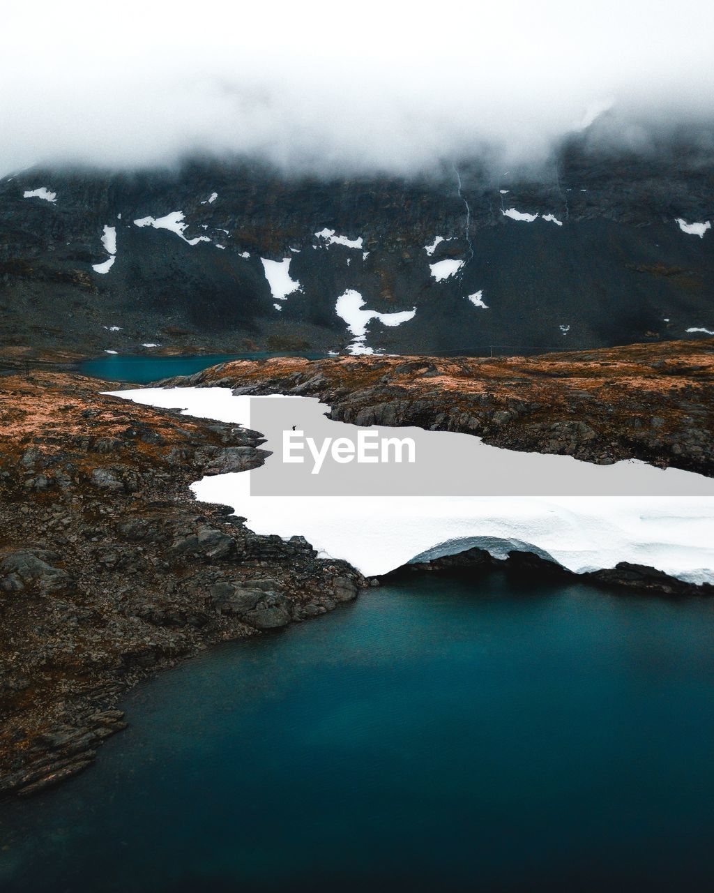 Scenic view of lake by snowcapped mountain against sky