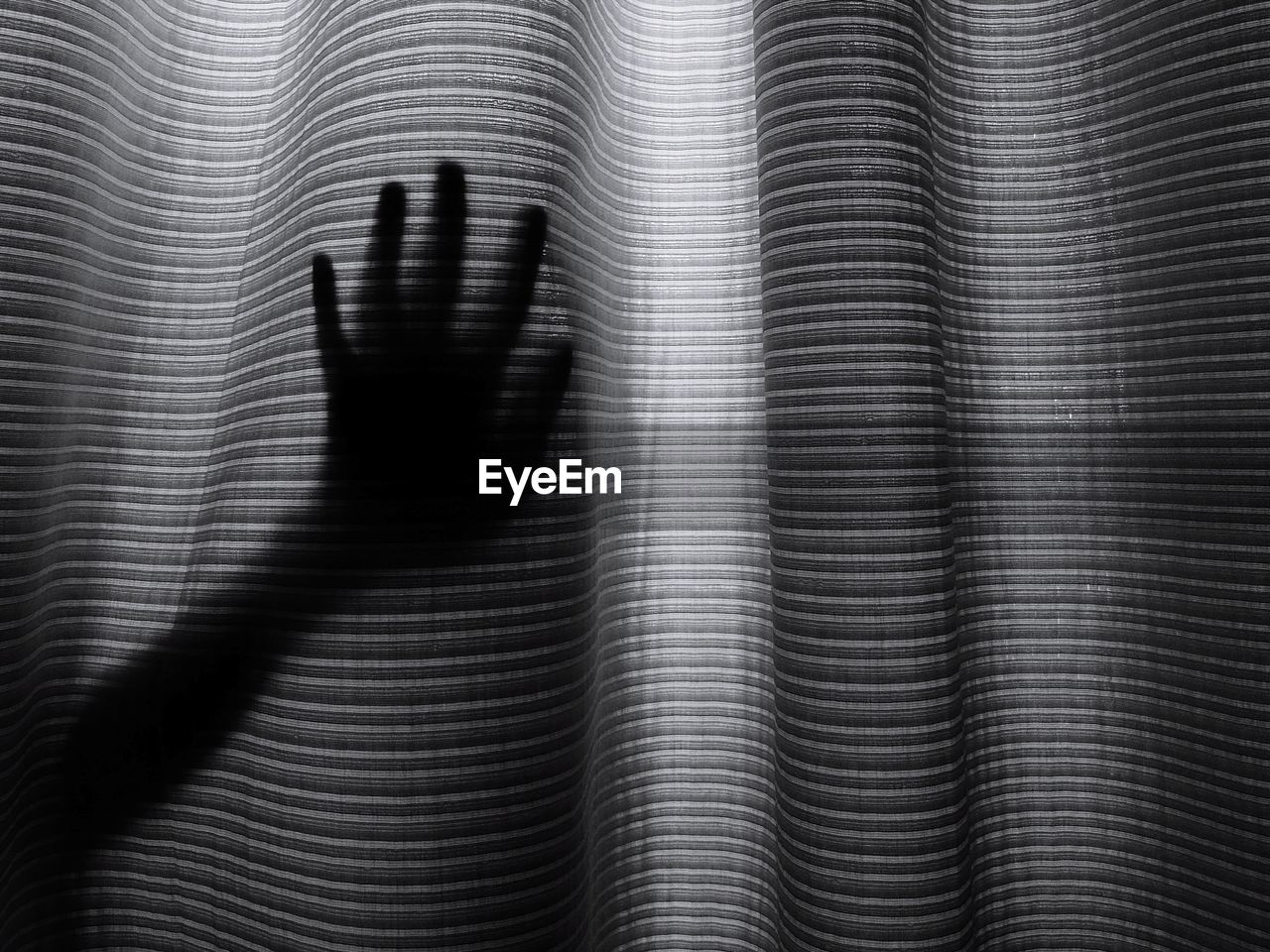 Silhouette hand touching curtain