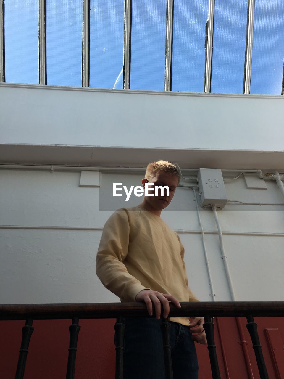 Low angle view of man standing by railing against skylight