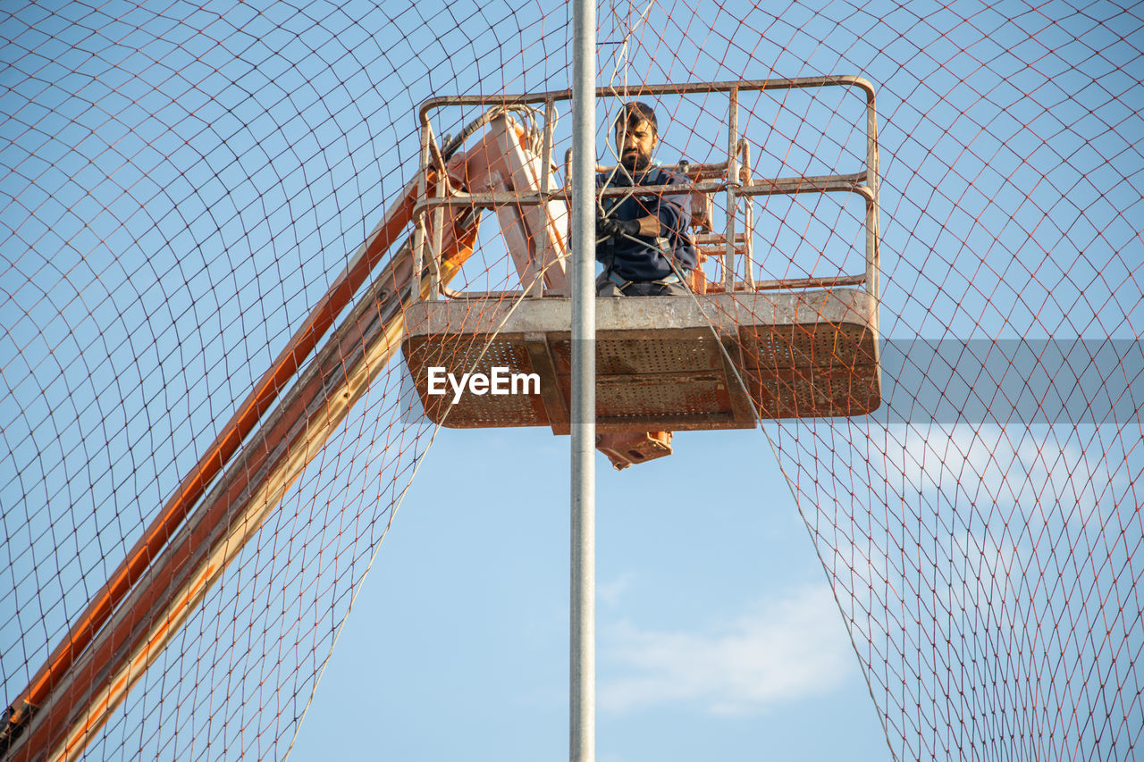 LOW ANGLE VIEW OF BASKETBALL HOOP ON FENCE AGAINST SKY