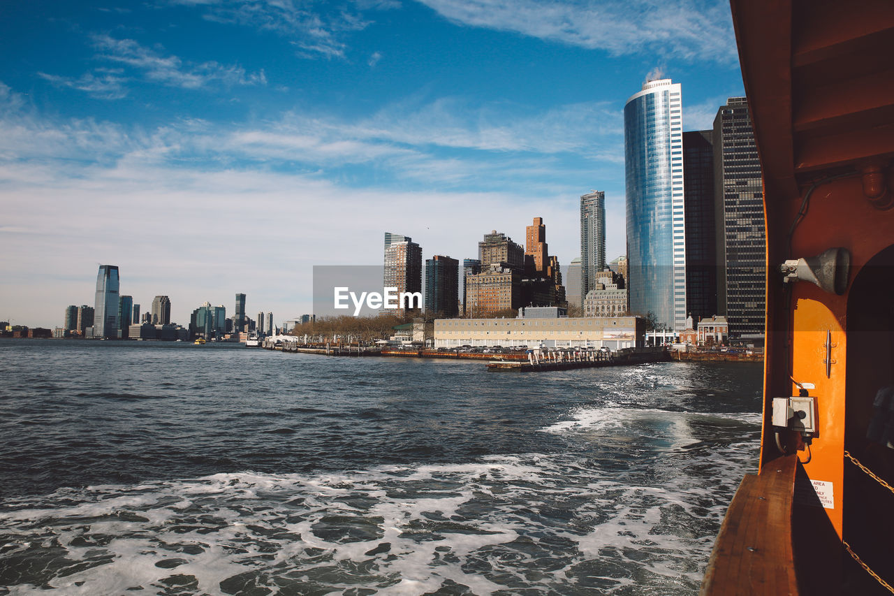 Sea by cityscape against sky