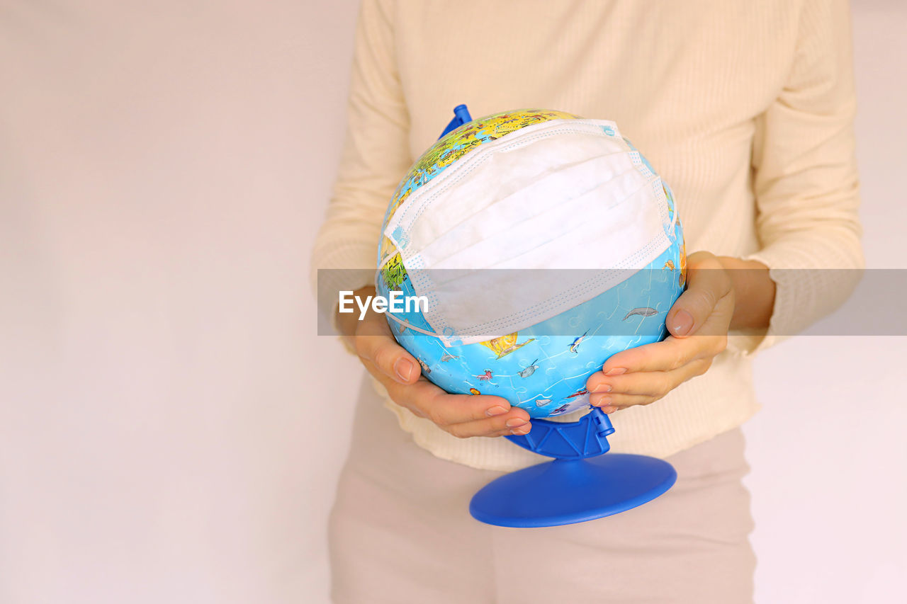Women's hands hold the globe in a medical mask. concept pandemic and environmental pollution. 