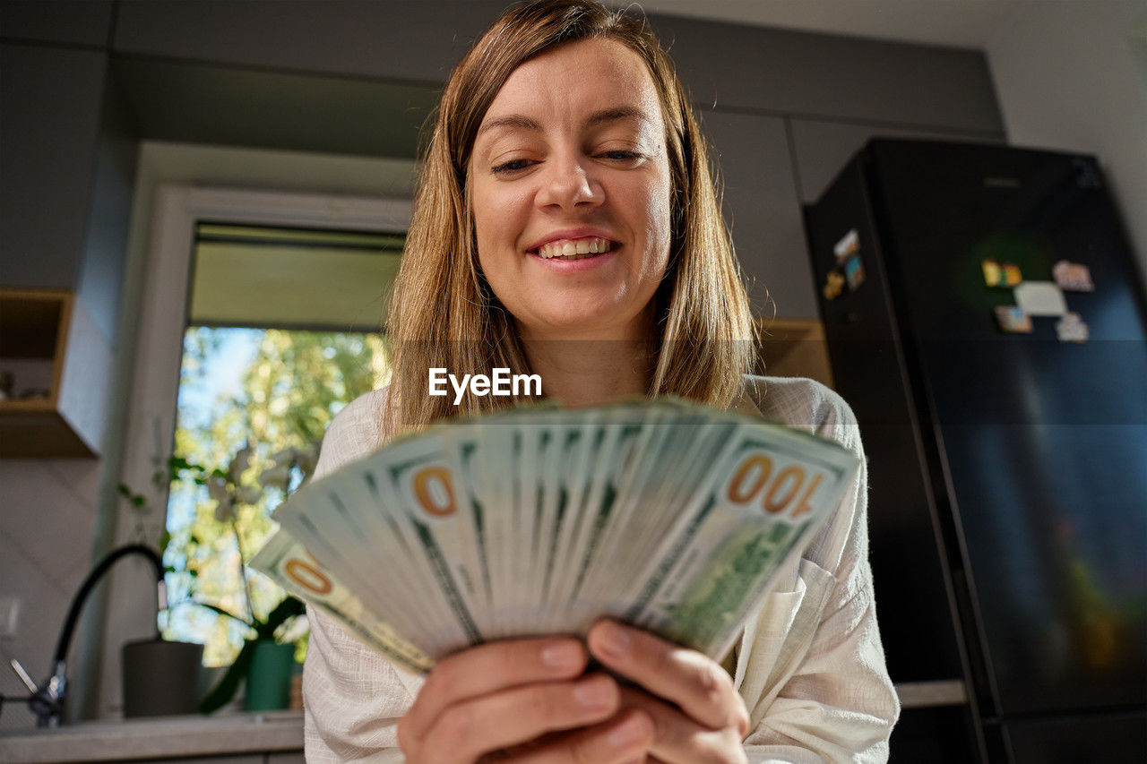 Happy woman counting dollar banknotes at home. budget planning