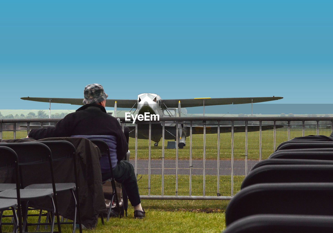 REAR VIEW OF MAN ON AIRPLANE