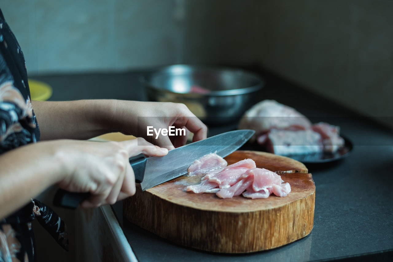 Midsection of woman cutting fish on wood