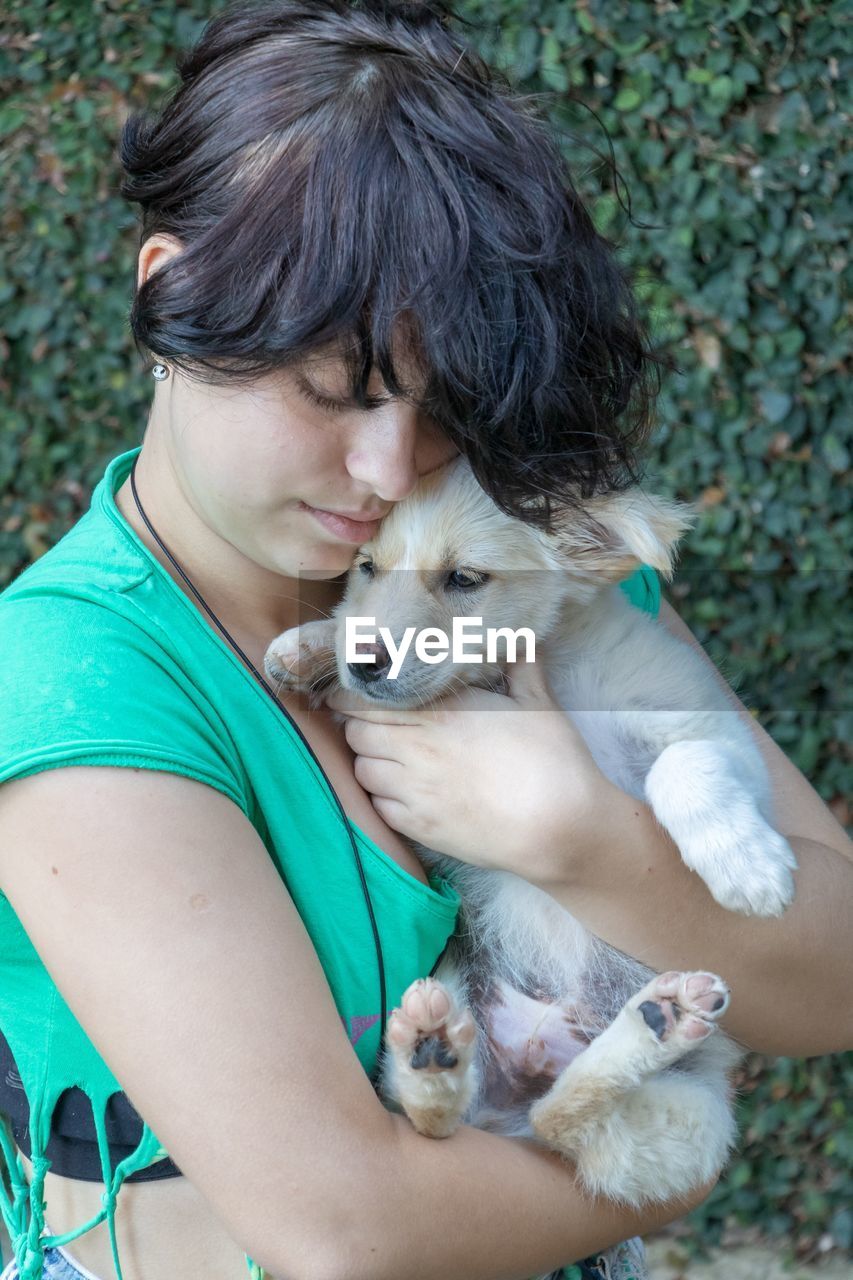 Woman embracing dog against plants