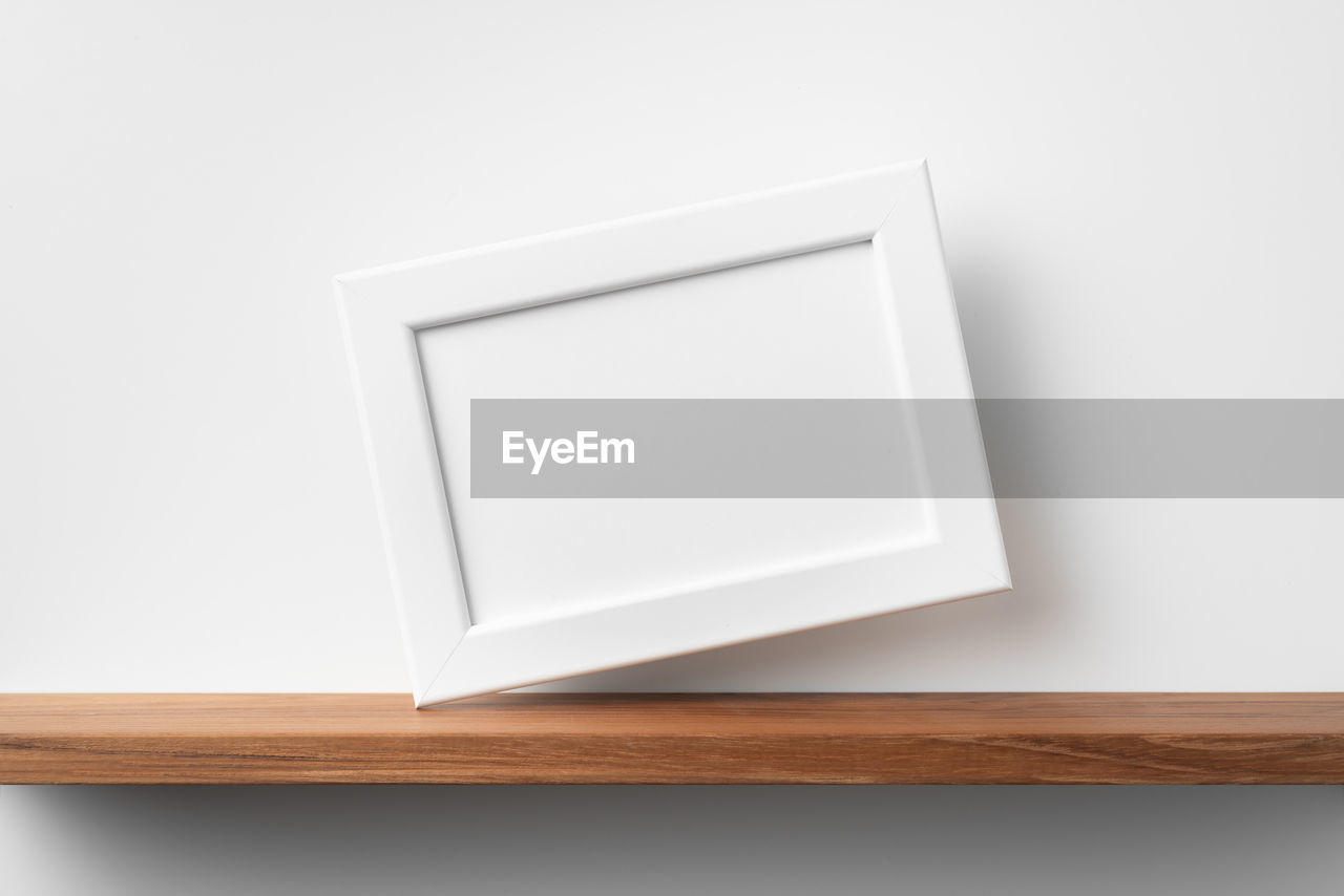HIGH ANGLE VIEW OF WHITE PAPER ON WOODEN TABLE AGAINST GRAY BACKGROUND