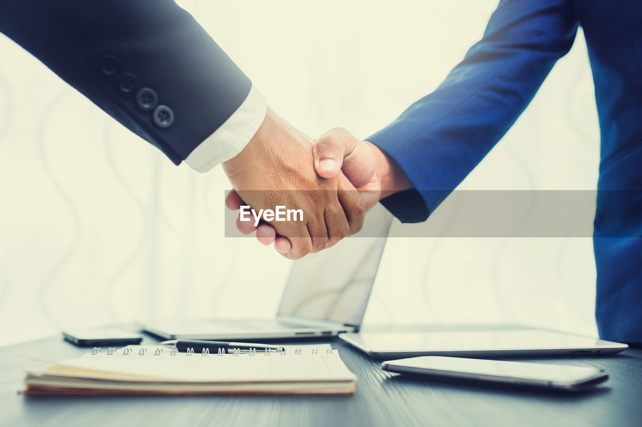 Cropped image of businessmen shaking hands at table