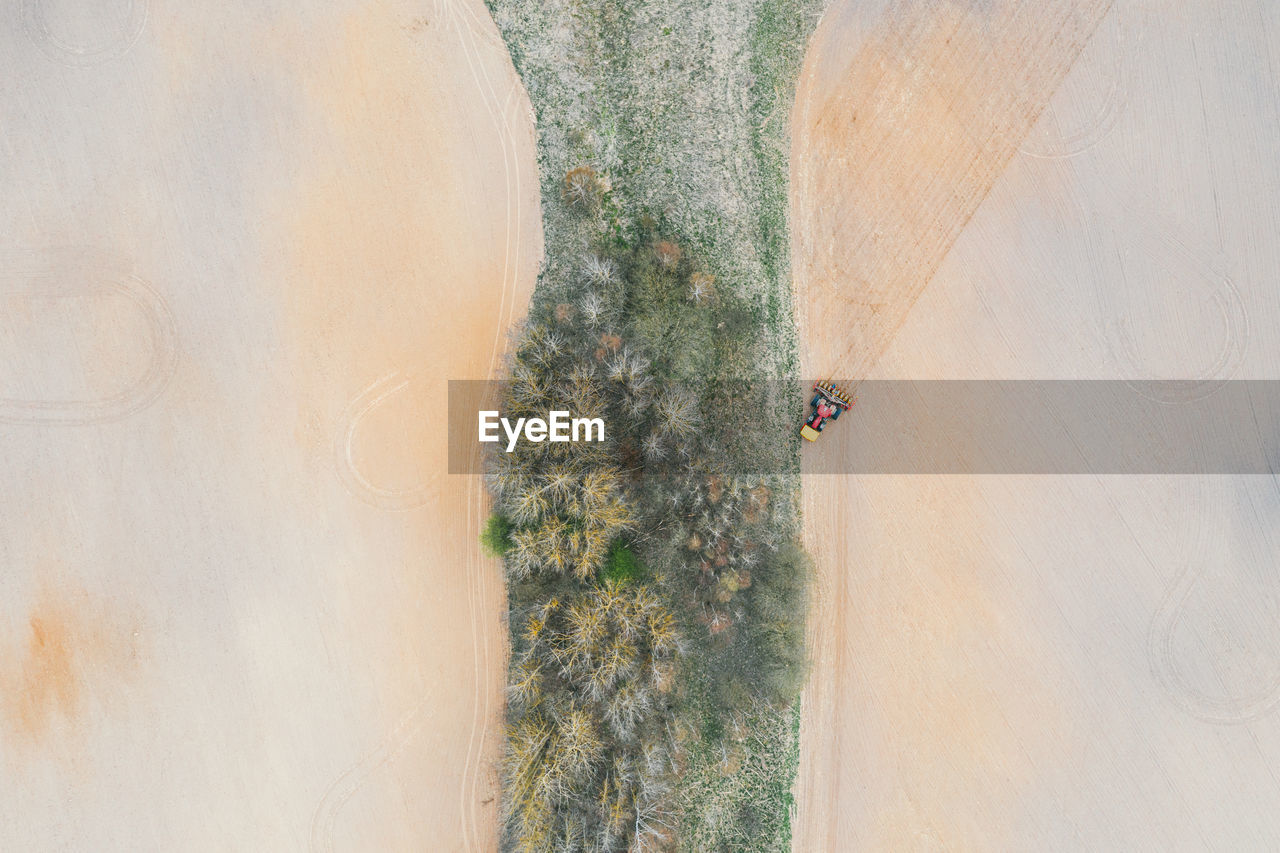 Lonely tractor on agricultural field with rows of plowed soil