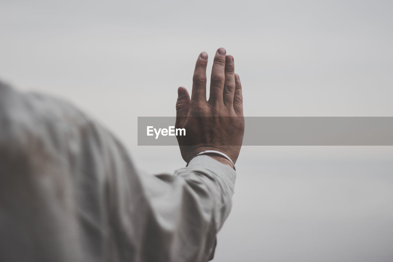 Midsection of man gesturing against sky