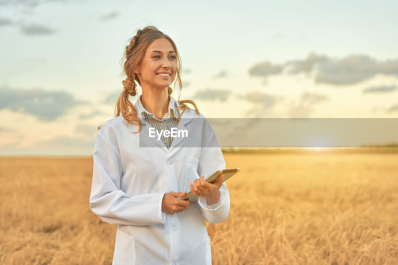 YOUNG WOMAN STANDING ON FIELD