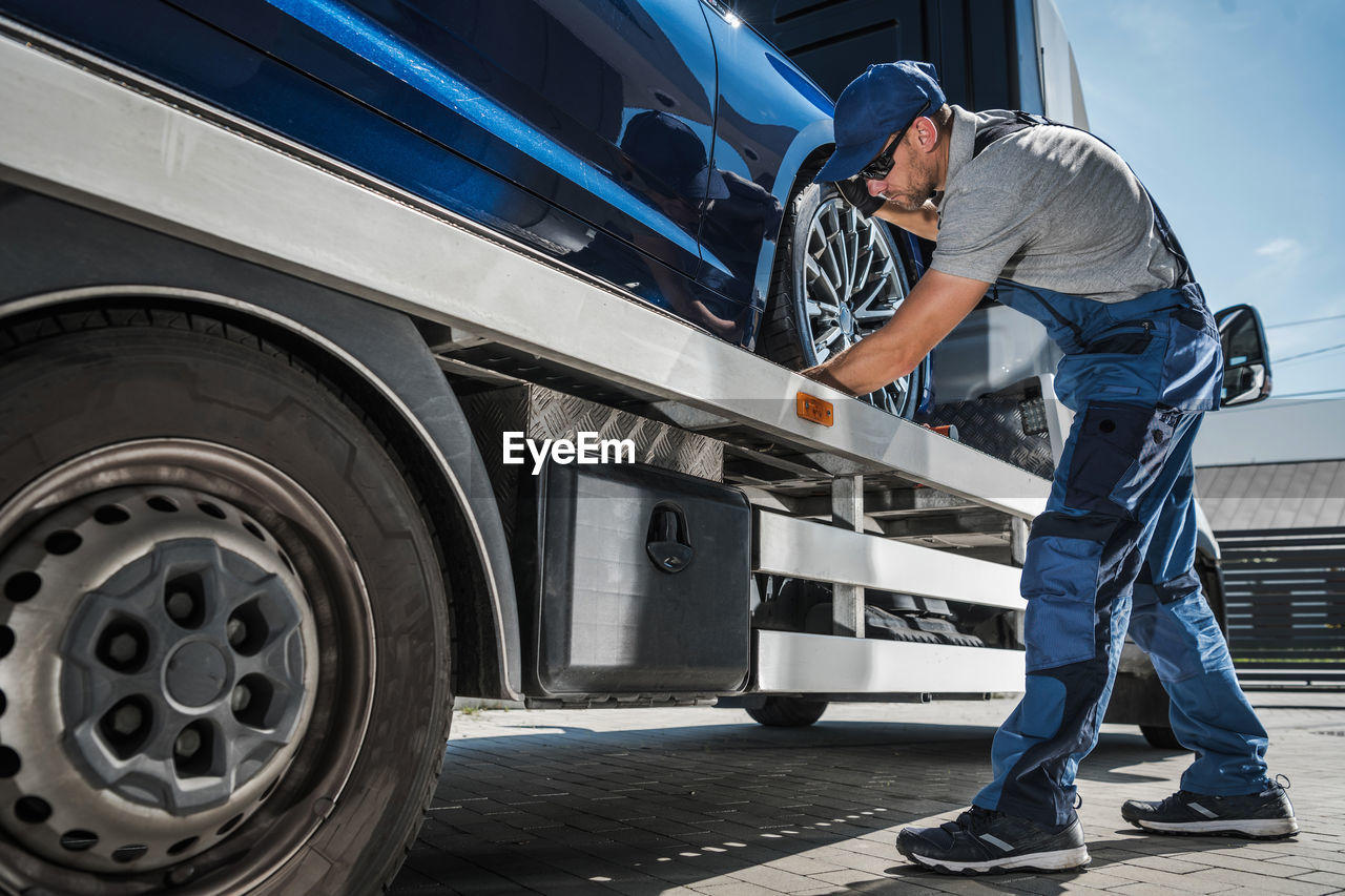 Tow truck driver preparing to safely deliver brand new car from dealer to buyer. 