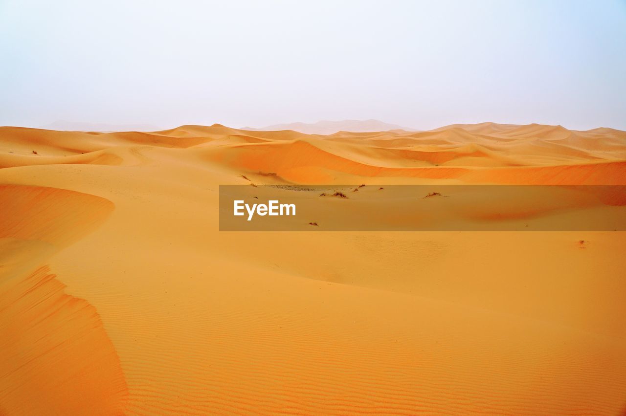 Sand dunes in desert against clear sky