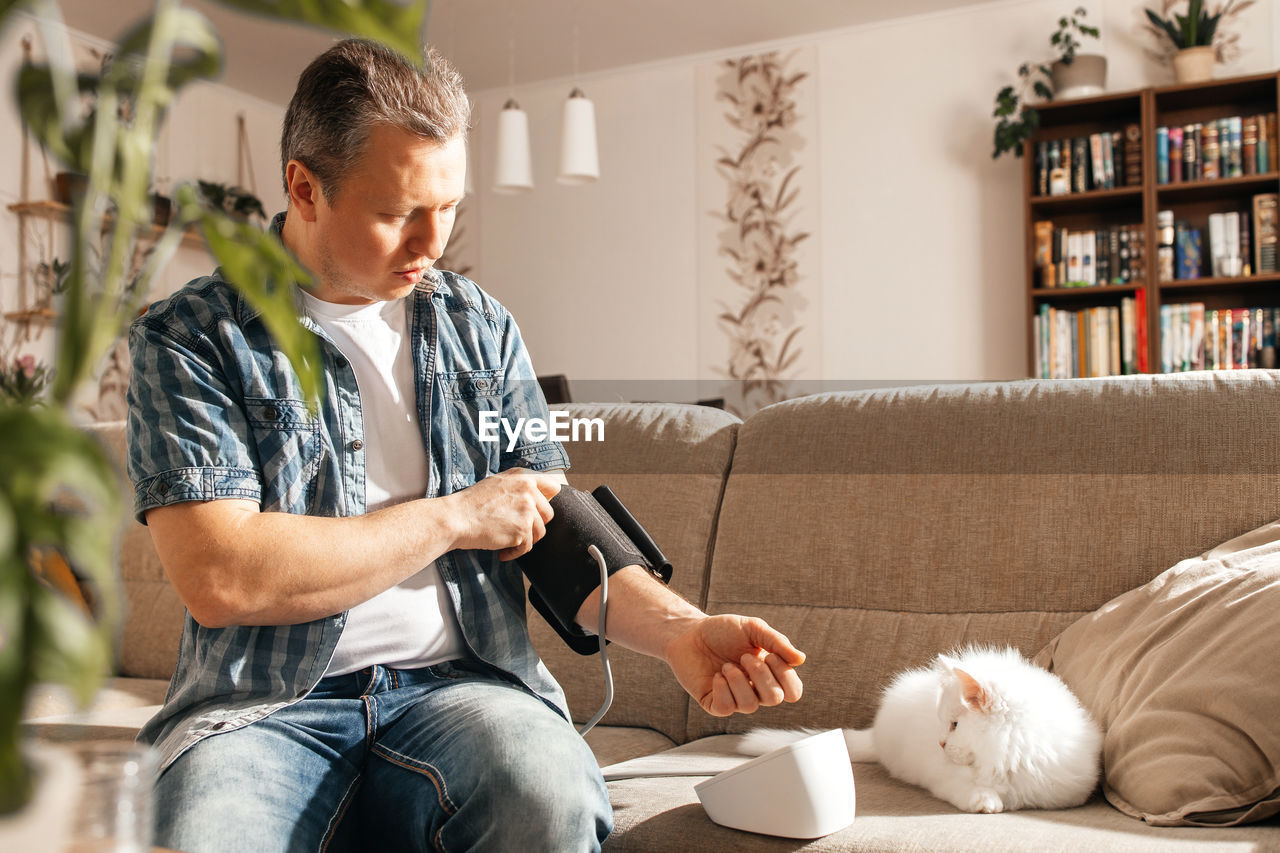 side view of young man using mobile phone while sitting on sofa at home