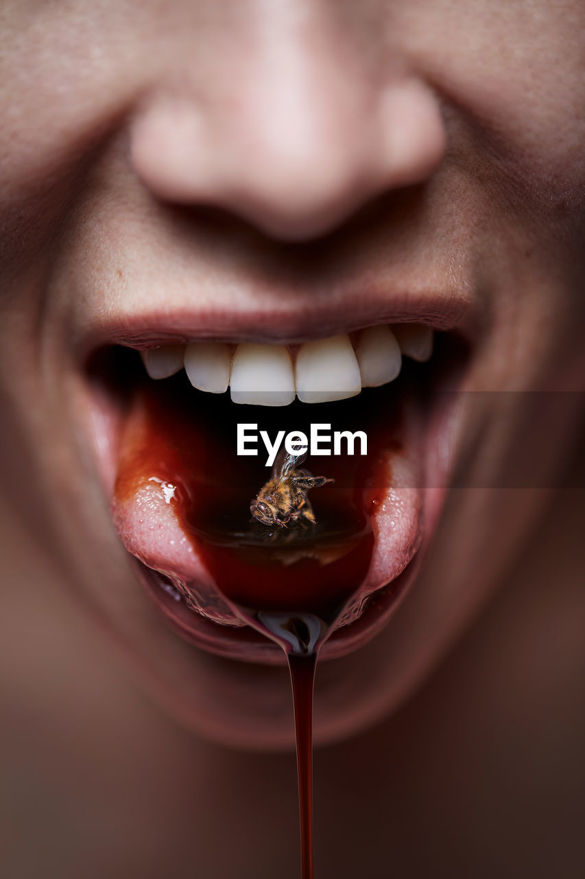 Cropped image of woman with dead bee in mouth