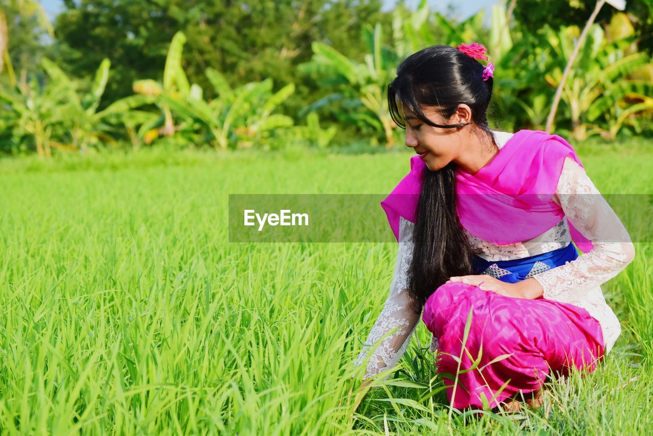 Balinese girl sitting on field