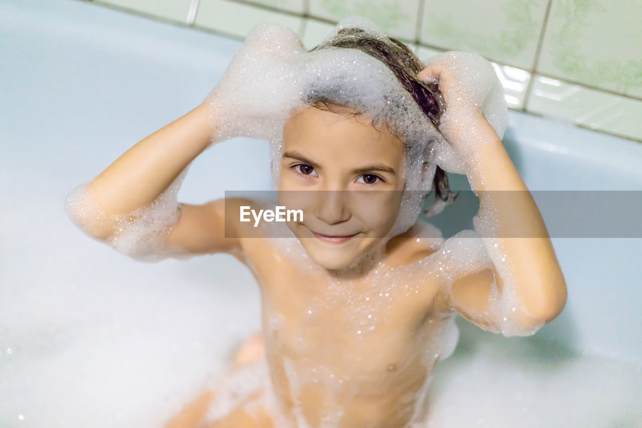 Portrait of girl taking bath in bathroom